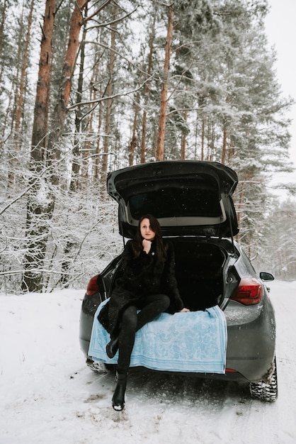 Portret van een vrouw op de achtergrond van een besneeuwd bos