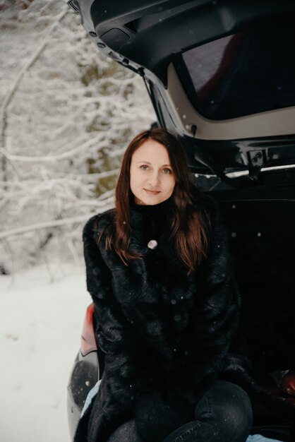 Portret van een vrouw op de achtergrond van een besneeuwd bos