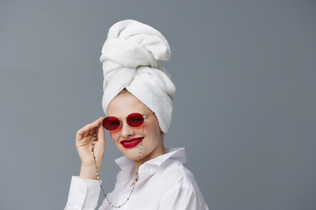 Portret van een vrouw rode bril handdoek op hoofd make-up geïsoleerde background