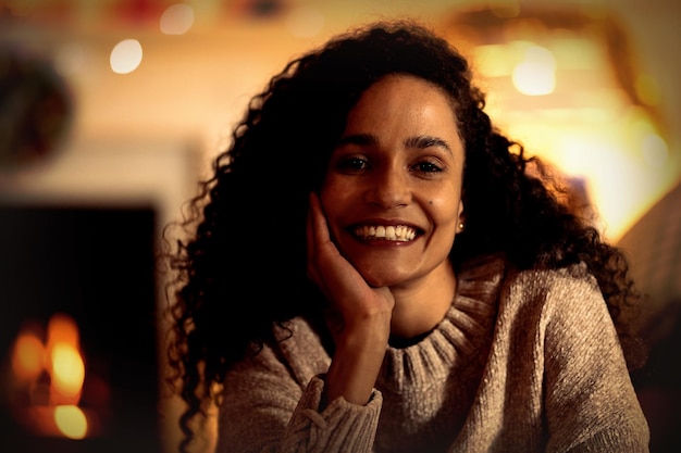 Portret van een vrouw van gemengd ras in haar zitkamer met Kerstmis, glimlachend naar de camera