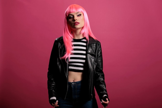 Portret van een vrouwelijk model met een stijlvol leren jack in de studio, zorgeloos en sensueel met een punkrockerstijl. roze haar hebben en funky zijn, glamour geweldige mode op de achtergrond.