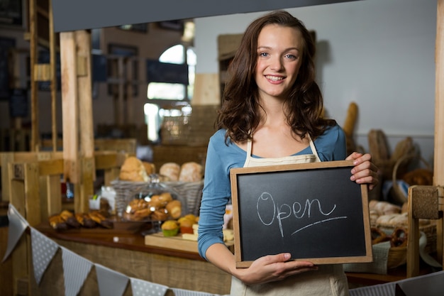 Portret van een vrouwelijk personeel dat een open teken houdt