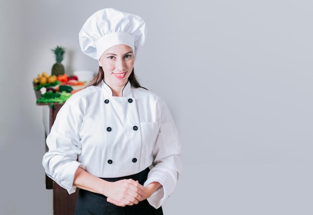 Portret van een vrouwelijke chef-kok omringd door verse groenten Portret van een vrouwelijke voedingsdeskundige in uniform met verse groenten op tafel Een vrouwelijke voedingsdeskundige met een tafel met groenten