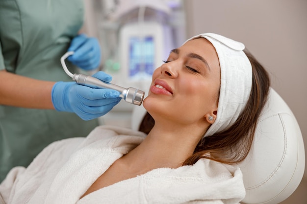 Portret van een vrouwelijke cliënt die een esthetische gezichtsbehandeling krijgt in een schoonheidssalon Verjonging hydratatie