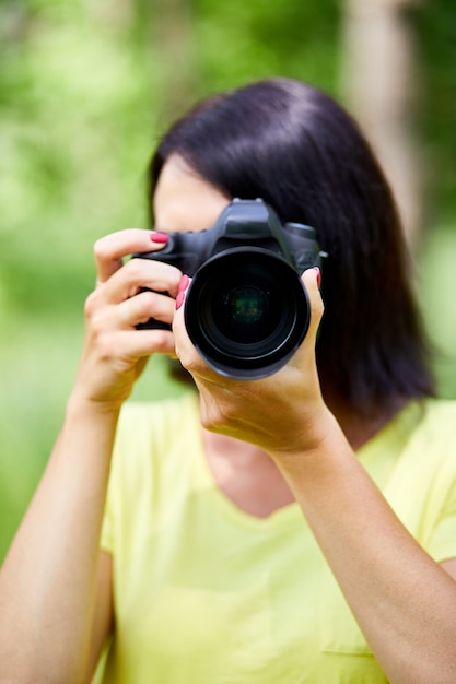 Portret van een vrouwelijke fotograaf die haar gezicht bedekt met de camera