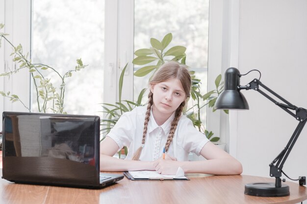 Portret van een vrouwelijke student die geniet van het leren in een coworking-kantoor met behulp van een laptopcomputer voor onderzoek, freelancer tijdens het maken van een project voor het maken van aantekeningen op afstand. leerling geconcentreerde tekennotities