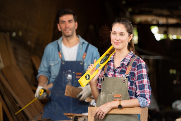 Portret van een vrouwelijke timmerman die voor een collega in een werkplaats staat