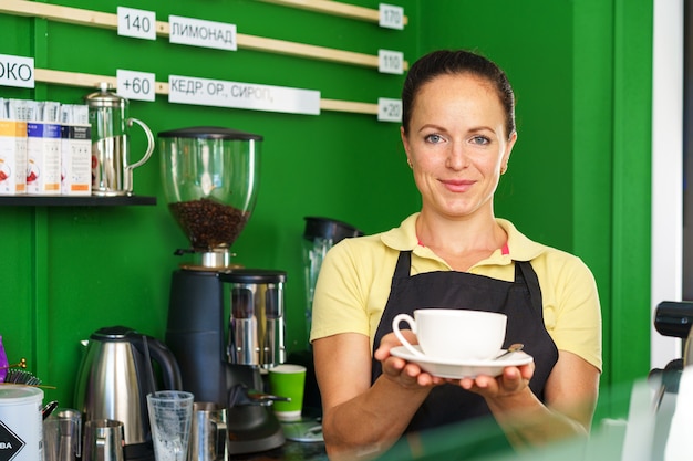 Portret van een vrouwenbarista in coffeeshop die zich bij balie bevindt