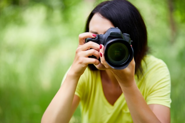 Portret van een vrouwenfotograaf die haar gezicht bedekt met de camera