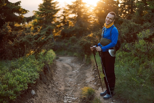 Foto portret van een wandelaar met wandelstokken en rugzak die bergwandelpaden beklimt of afdaalt