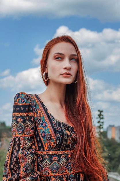 Portret van een wilskrachtige vrije sterke roodharige vrouw in een etnische jurk in de buurt van een grote steen Een symbool van ontembaarheid Carrière Mode foto Concept