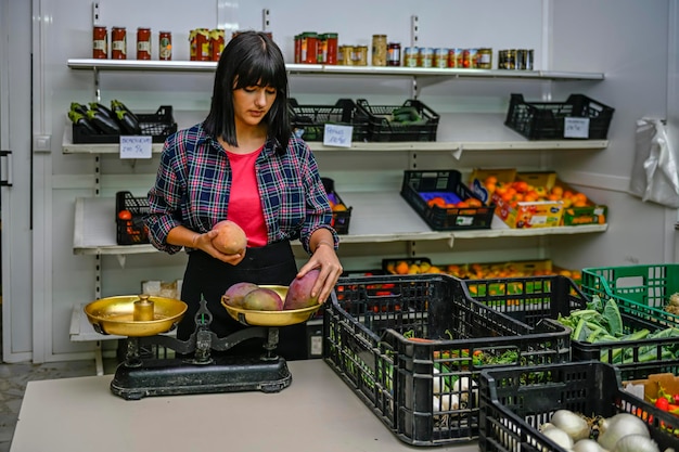 Portret van een winkelier in de fruitwinkel die enkele rijpe avocado's weegt