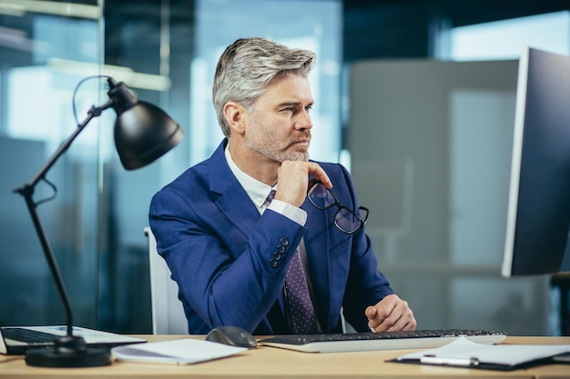 Portret van een zakenman die denkt terwijl hij op kantoor op de computer werkt