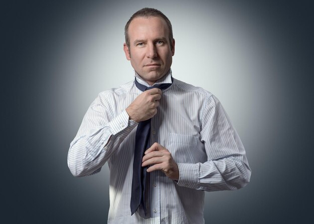 Foto portret van een zakenman die zich kleedt tegen een grijze achtergrond