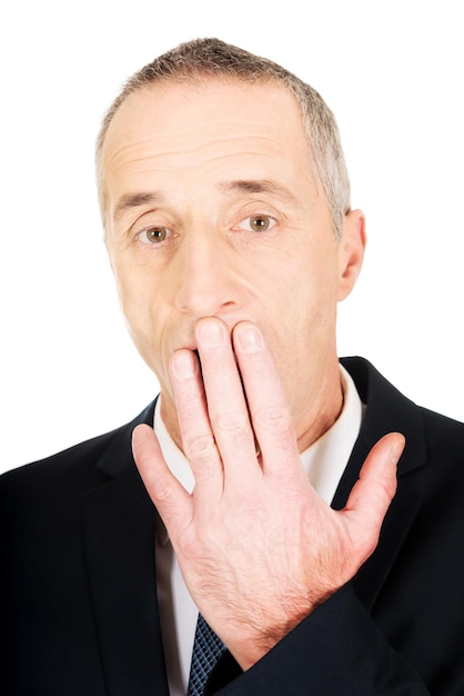 Foto portret van een zakenman die zijn mond met zijn hand bedekt tegen een witte achtergrond
