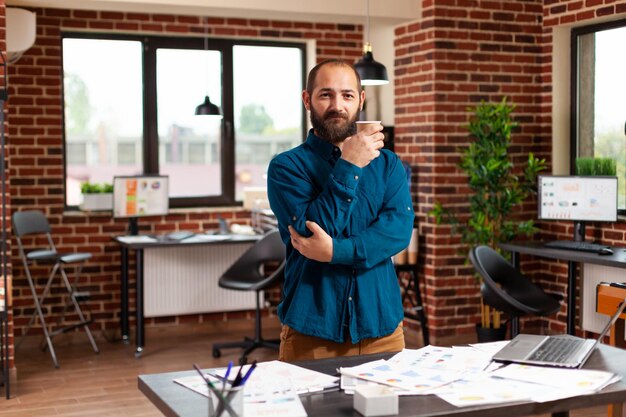 Foto portret van een zakenman met een koffiekop in zijn kantoor