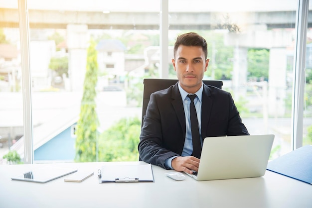 Portret van een zakenman met een laptop terwijl hij op kantoor zit