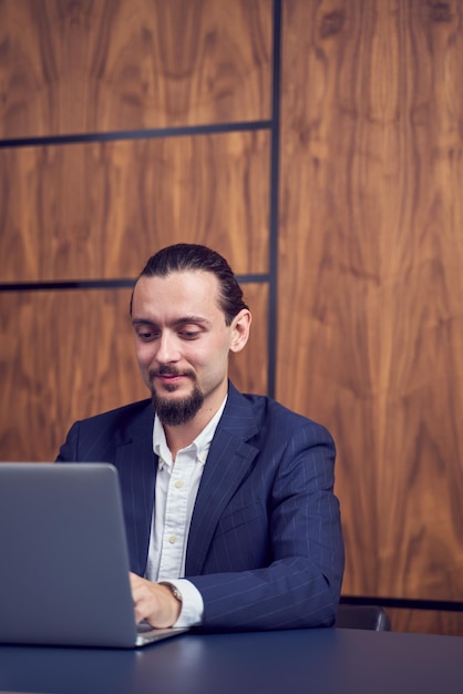 Portret van een zakenman met een laptop terwijl hij op tafel zit