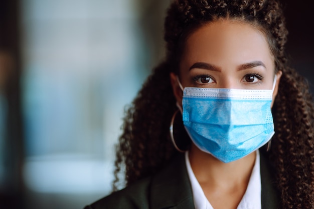 Portret van een zakenvrouw die een beschermend masker draagt en in de camera kijkt.