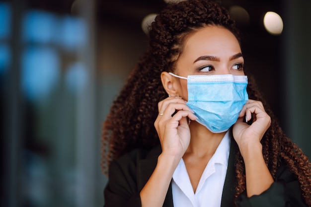 Portret van een zakenvrouw die een beschermend masker draagt en in de camera kijkt.