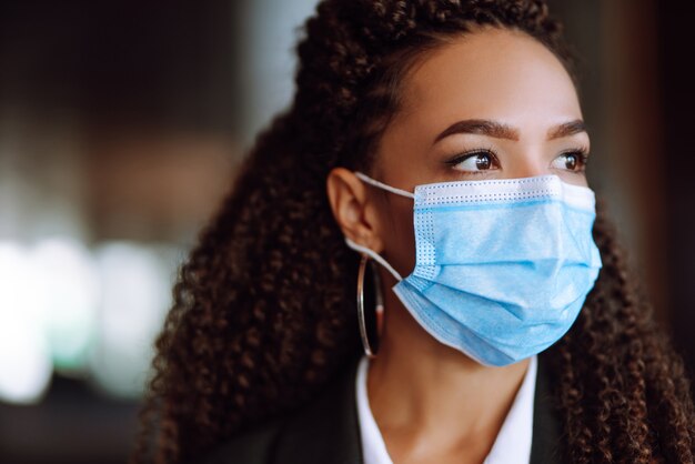 Portret van een zakenvrouw die een beschermend masker draagt en in de camera kijkt.
