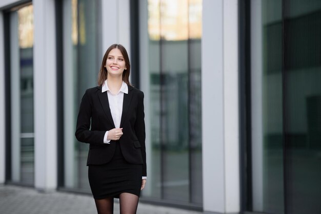 Portret van een zakenvrouw Een gelukkige zakenvrouw loopt in de buurt van een kantoorgebouw