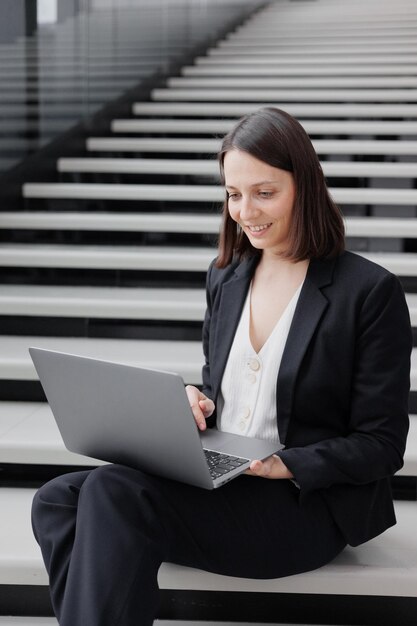 Foto portret van een zakenvrouw met een laptop terwijl ze op de trappen zit
