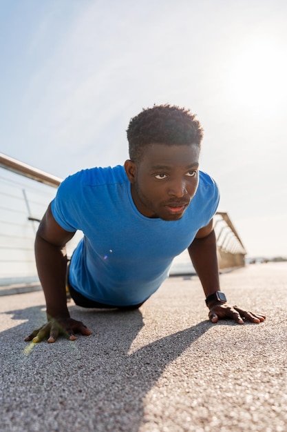Portret van een zelfverzekerde Afrikaanse man die push-ups doet en buiten traint Gezondheidslevensstijl