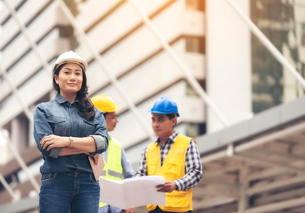 Portret van een zelfverzekerde architect met arbeiders op de achtergrond