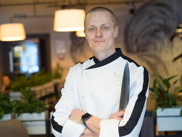 Foto portret van een zelfverzekerde chef-kok met gekruiste armen die in een restaurant staat