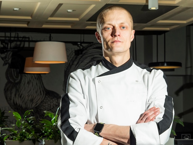 Foto portret van een zelfverzekerde chef-kok met gekruiste armen die in een restaurant staat