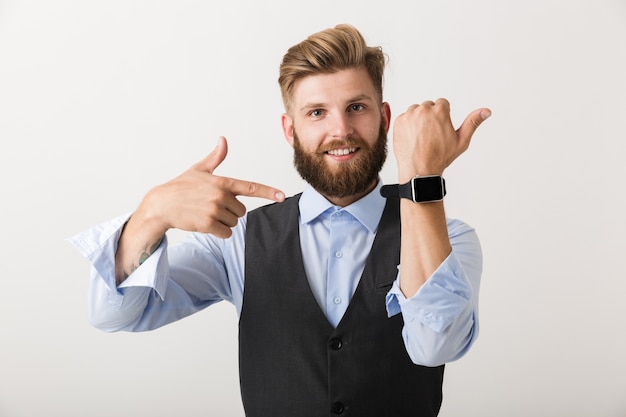 Portret van een zelfverzekerde jonge, bebaarde zakenman die zich geïsoleerd over witte muur bevindt, die slim horloge draagt