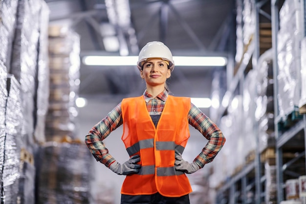 Portret van een zelfverzekerde magazijnmedewerker in beschermende werkkleding die in de faciliteit staat