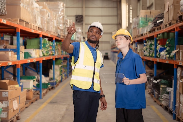 Portret van een zelfverzekerde mannelijke supervisor en vrouwelijke medewerkers die samen werken in een magazijn met een tablet.