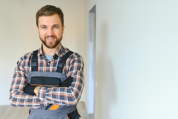 Portret van een zelfverzekerde reparateur met baard die in een leeg appartement staat