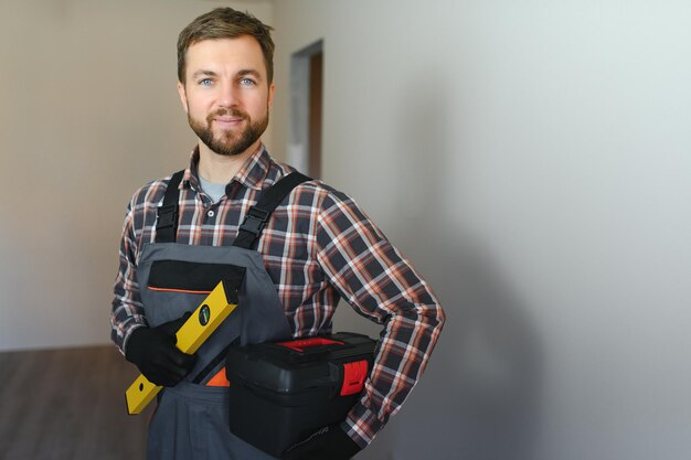 Portret van een zelfverzekerde reparateur met baard die in een leeg appartement staat