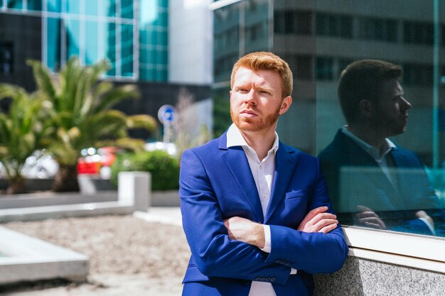 Portret van een zelfverzekerde roodharige zakenman met gekruiste armen