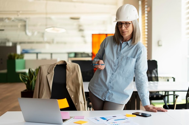 Portret van een zelfverzekerde, serieuze senior vrouw architect-ingenieur die een laptopwerkproject gebruikt en naar een computermonitor kijkt die in een modern kantoor staat. Succesvol bedrijfsconcept