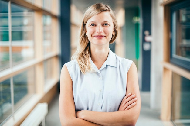 Foto portret van een zelfverzekerde vrouw met gekruiste armen die in de lobby staat