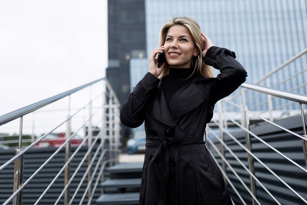 Portret van een zelfverzekerde zakenvrouw van middelbare leeftijd die op een mobiele telefoon praat tegen de achtergrond van