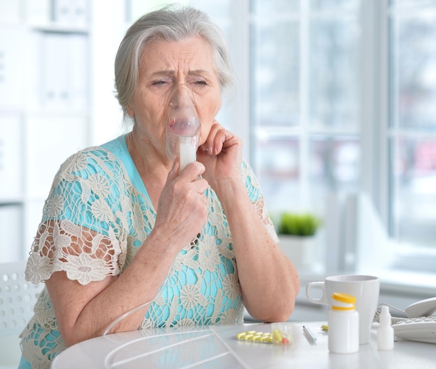 Portret van een zieke oudere vrouw die inhaleert