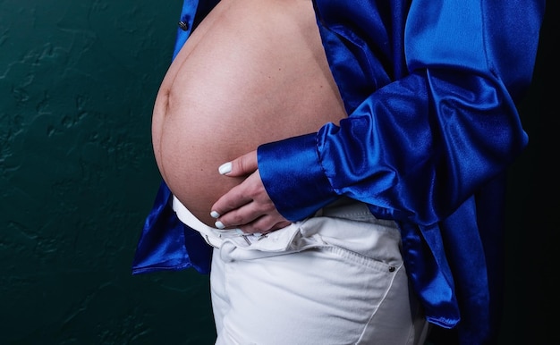 Portret van een zwangere blanke vrouw die haar handen op de buik van de baby houdt