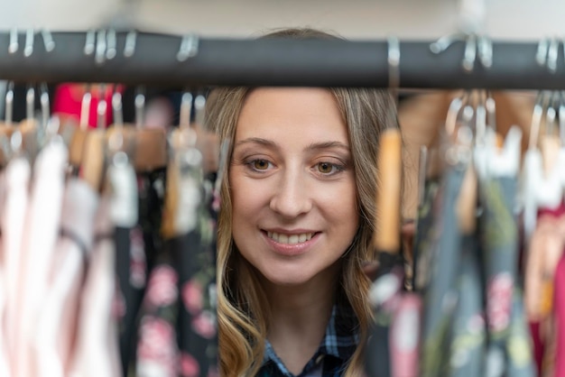 Portret van een zwangere blonde jonge vrouw die kleding zoekt in een kledingwinkel