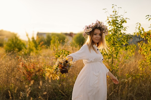 Portret van een zwangere vrouw een mooie jonge zwangere vrouw in een witte jurk loopt in het veld