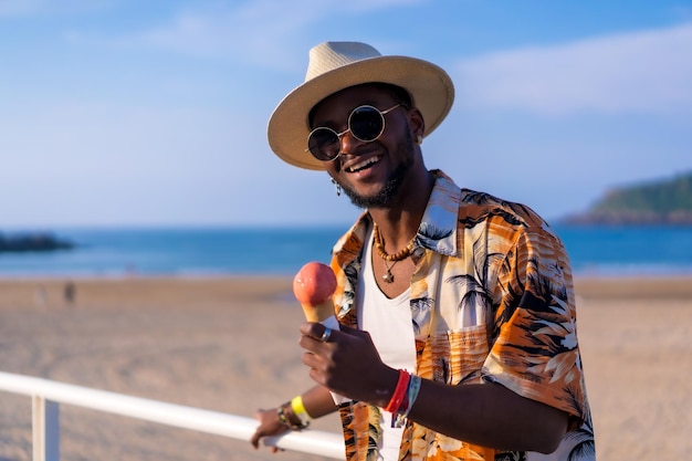 Portret van een zwarte etnische man geniet van zomervakantie op het strand en eet ijs