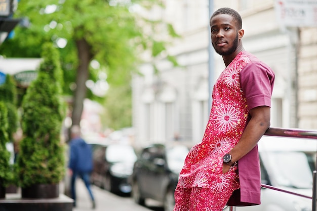 Portret van een zwarte jonge man die Afrikaanse traditionele rode kleurrijke kleding draagt.