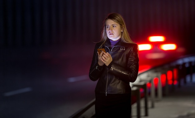 Portret van eenzame vrouw die zich voordeed op donkere snelweg