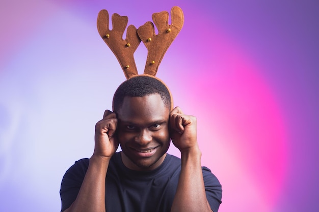 Portret van emotionele Afro-Amerikaanse man draagt rudolph hertenhoorns geniet van zijn accessoire voor