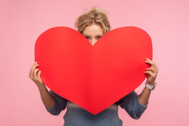 Portret van emotionele blonde vrouw op roze achtergrond