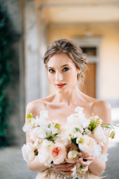 Portret van ernstige bruid in een jurk met een boeket roze bloemen